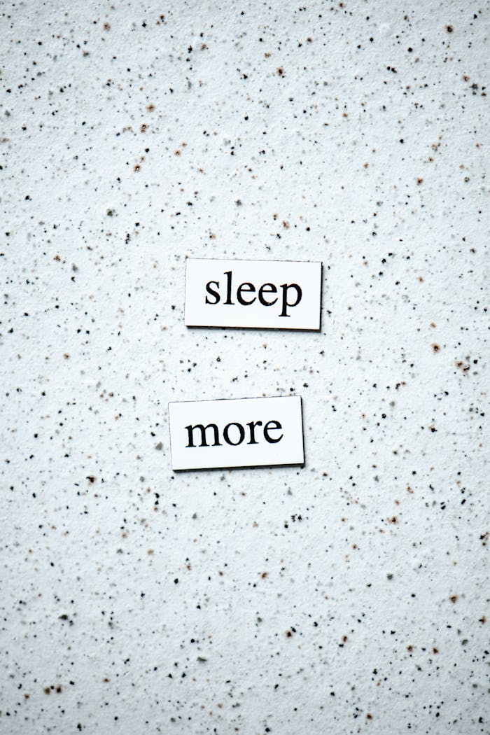 Motivational quote 'sleep more' on a minimalist speckled surface.